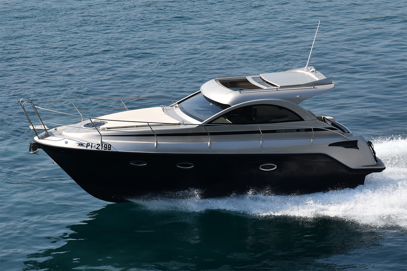 Moderna motorna jahta Mirakul 30 sa srebrnim i tamnim trupom plovi po plavom moru, ostavljajući izražen bijeli trag