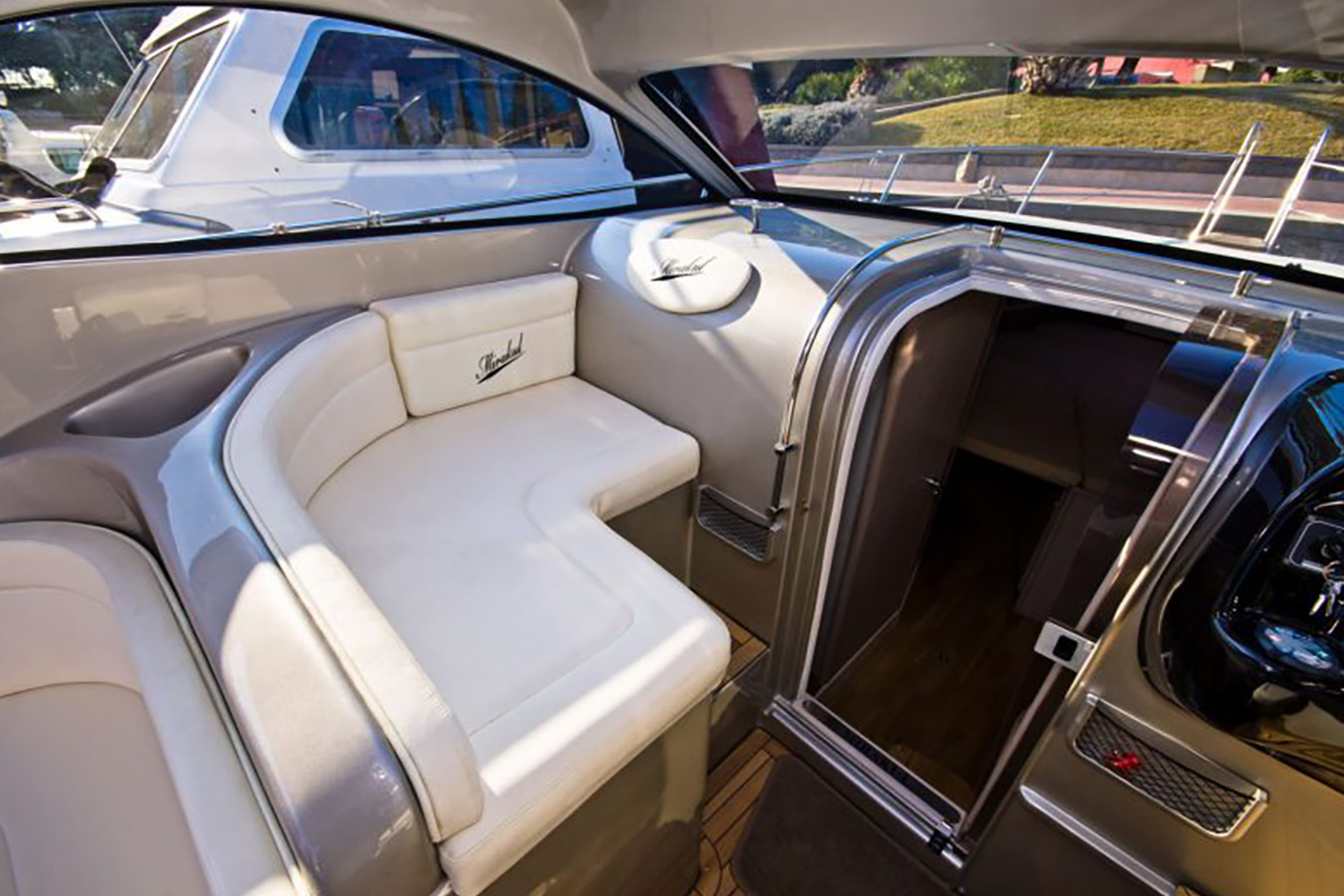 Unutrašnjost kokpita jahte Mirakul 30, prikazuje elegantna bijela sjedala u obliku slova U, upravljačku konzolu i ulaz u kabinu