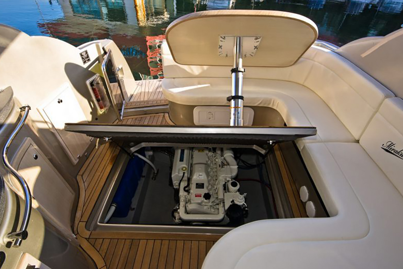 Detaljan prikaz unutrašnjosti sportske jahte s otvorenim motornim prostorom, otkrivajući uredan brodski motor ispod tikovine i udobnih sjedala