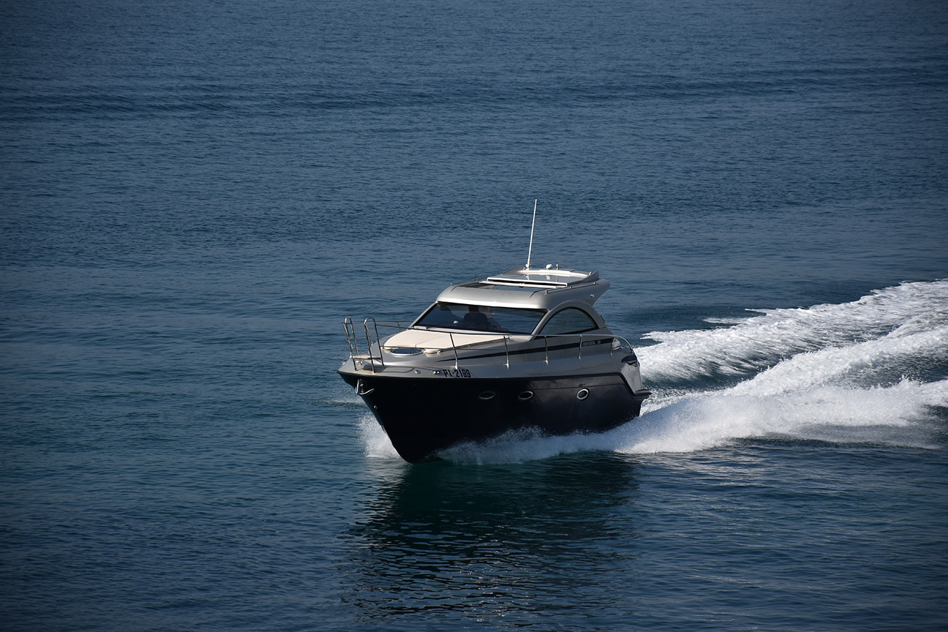 Elegantna srebrno-tamnosiva motorna jahta Mirakul 30 juri mirnim plavim morem, ostavljajući za sobom bijeli trag