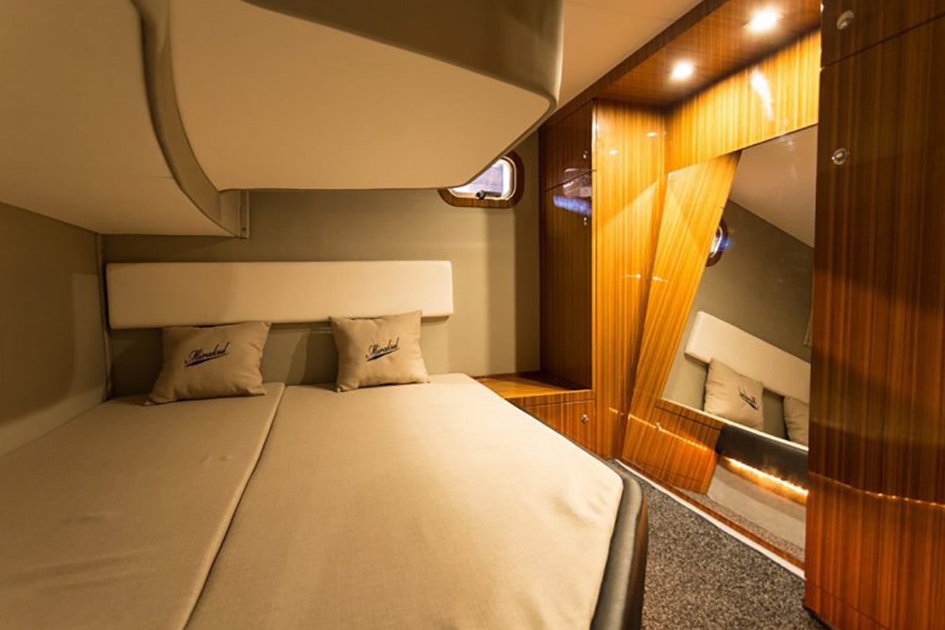 Pomoćna kabina Mirakul 40 s dva ležaja, bočnim prozorom i velikim zrcalom uz ormar od drva — intiman noćni prostor luksuzne jahte