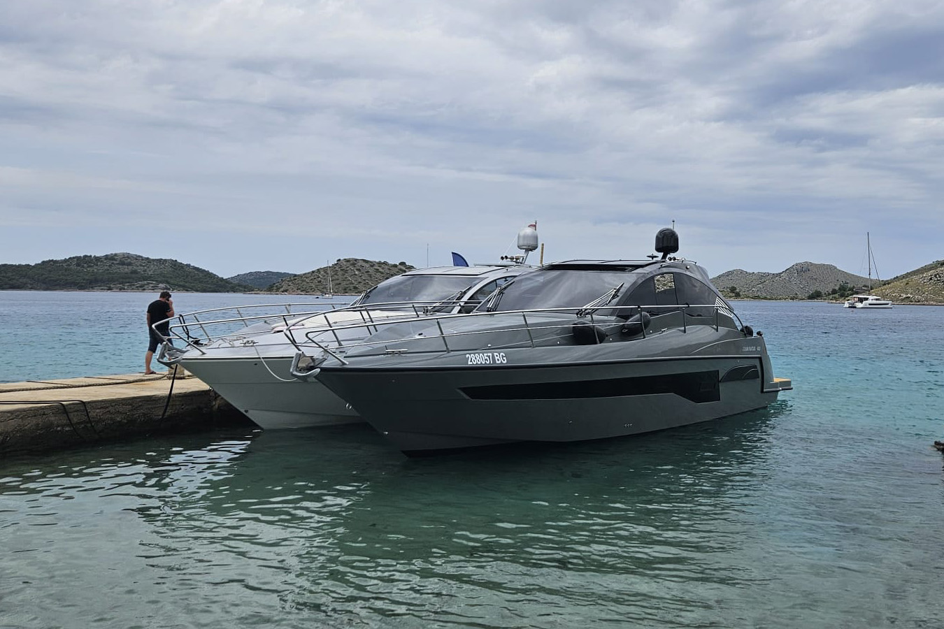 Dva primjerka Mirakul 40, luksuzna jahta privezana uz gat u tirkiznoj uvali; tamno sivi i svijetlo sivi trupovi s zatamnjenim staklima