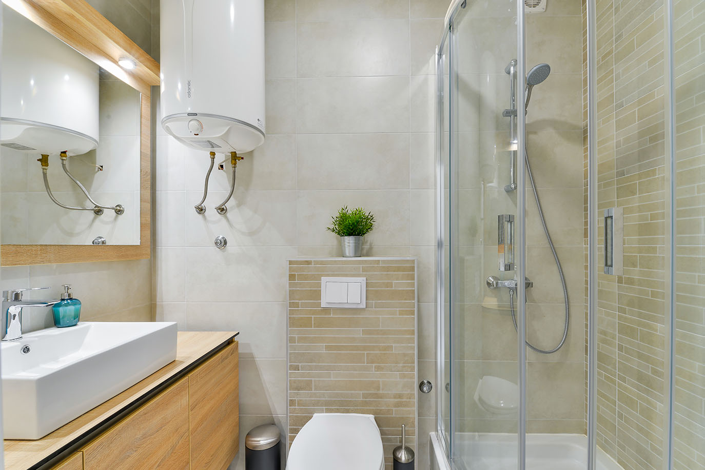 Moderna i elegantna kupaonica s bijelim nadpultnim umivaonikom na drvenoj komodi, visećom WC školjkom i prostranom staklenom tuš kabinom, tipična za luksuzni smještaj