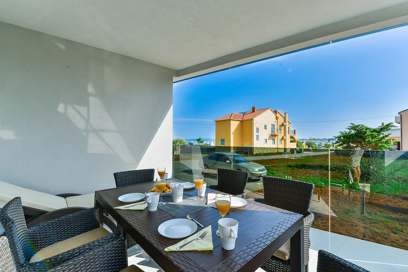 Šarmantan vanjski blagovaonski prostor s postavljenim stolom, pletenim stolicama i svježim doručkom, nudeći predivan pogled, idealan za goste u apartmanima na Viru