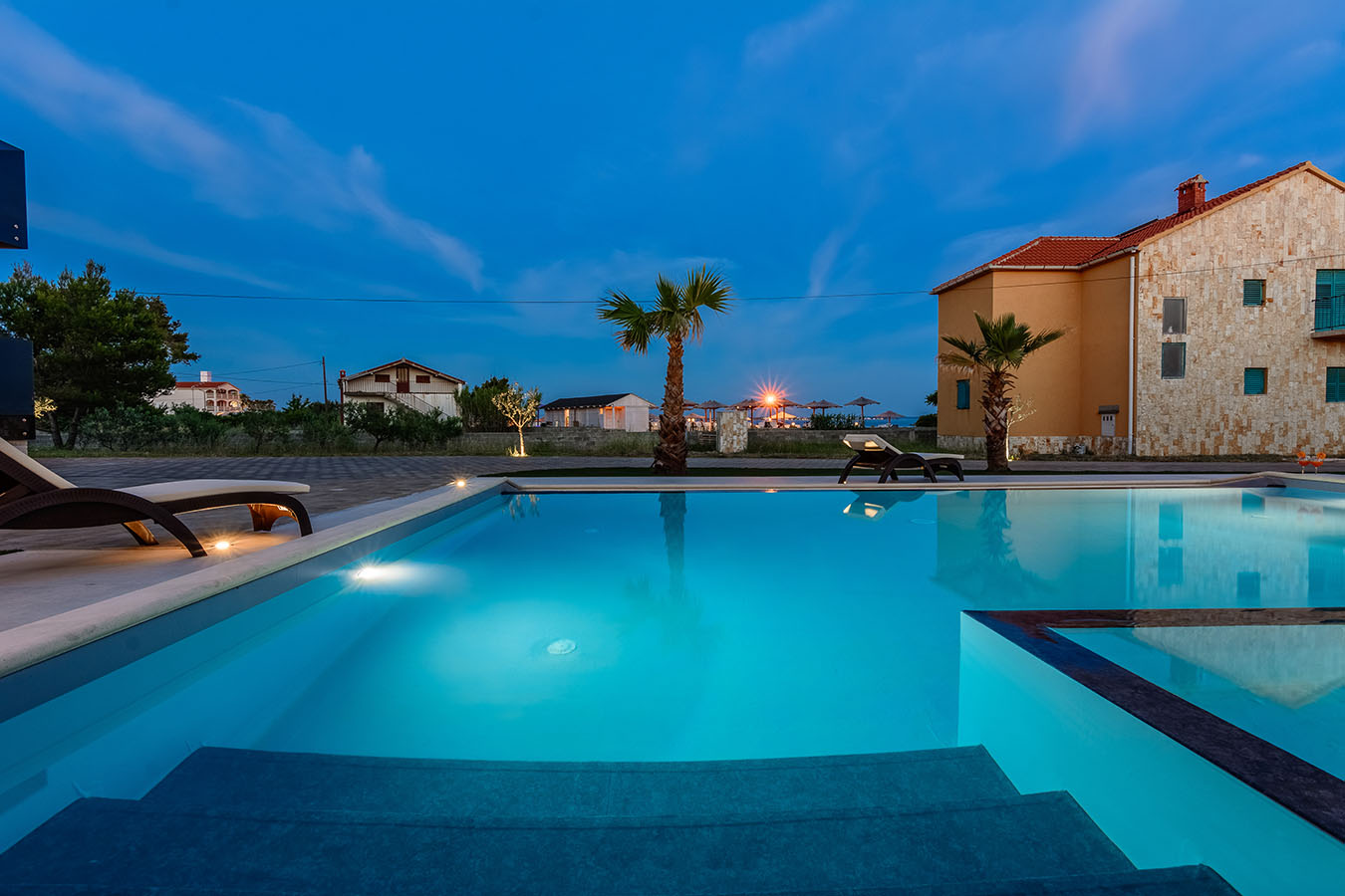 Noćni kadar bazena s palmama i ambijentalnom rasvjetom – udoban smještaj na otoku Viru