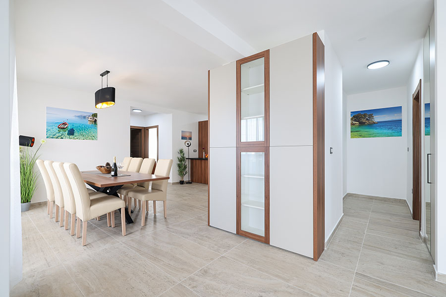 Prostrana blagovaonica s modernim drvenim stolom, bež tapeciranim stolicama i elegantnom crnom visilicom, koja nudi luksuzni smještaj