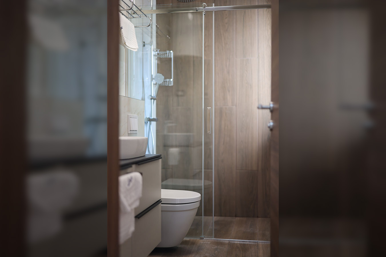 Moderna kupaonica s bijelim umivaonikom, ormarićem, WC-om i staklenom tuš kabinom, kao dio luksuznog smještaja