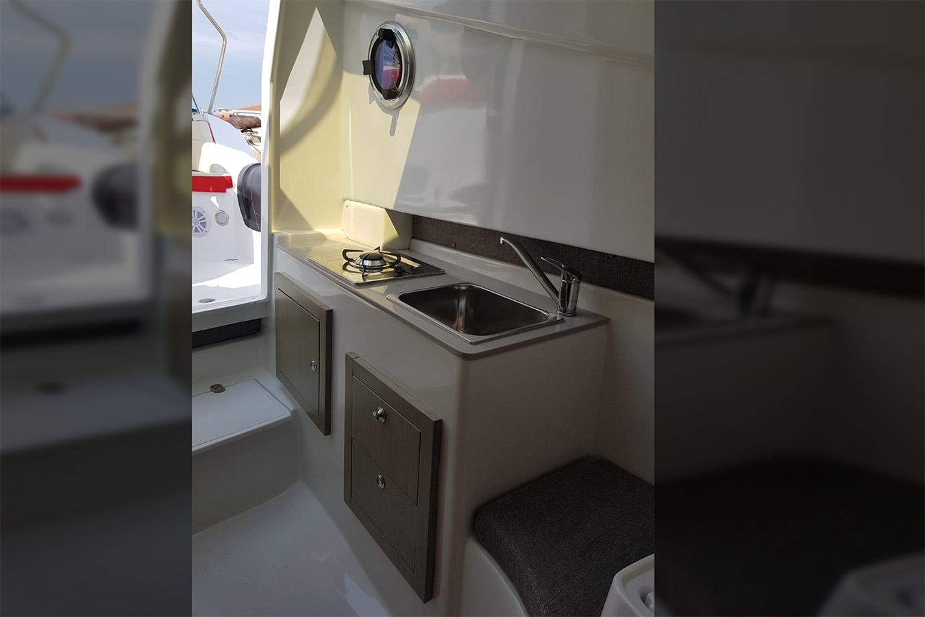 Kompaktna i moderna kuhinja (galija) unutar plovila, sa sudoperom od nehrđajućeg čelika, plinskim štednjakom na jedan plamenik i drvenim ormarićima za pohranu, karakteristična za model Shark 38