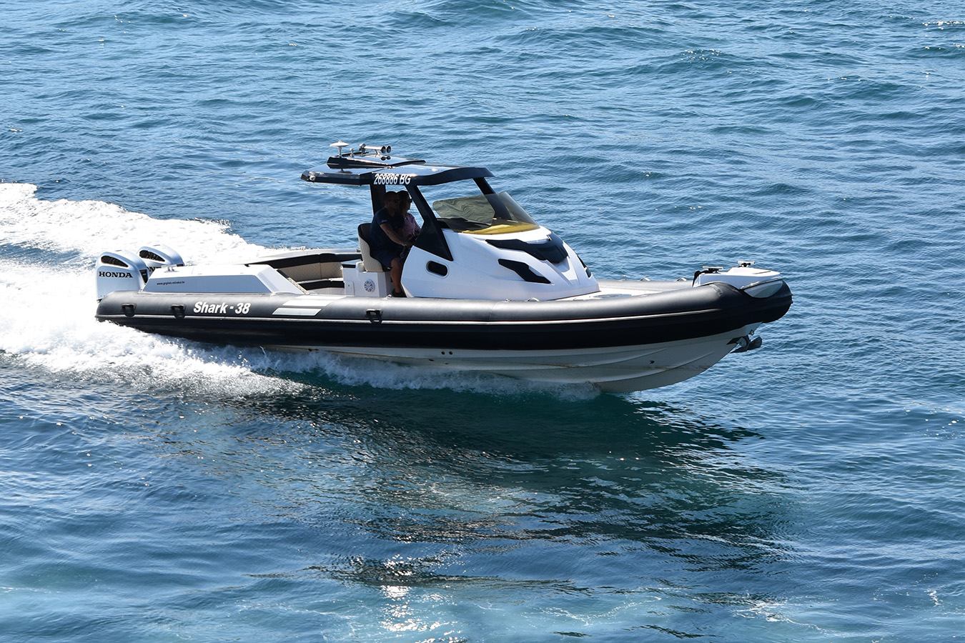 Moderan bijelo-crni luksuzni gumenjak s dva Honda motora juri plavim morem, ostavljajući trag