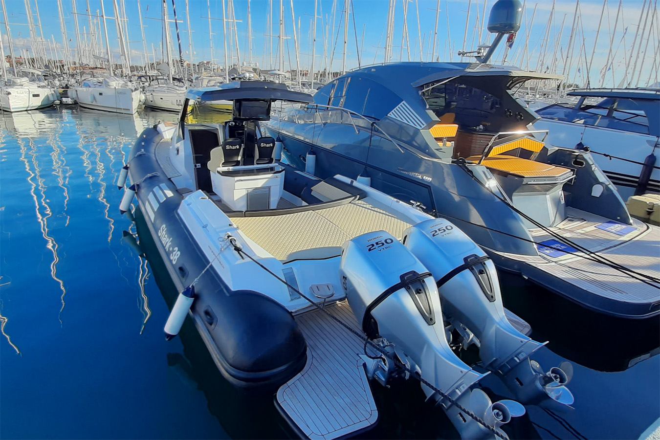 Elegantan luksuzni gumenjak s dva vanbrodska motora Honda usidren je u sunčanoj marini, pored veće jahte