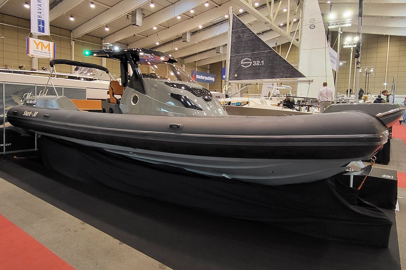 Elegantan sivi luksuzni gumenjak izložen na sajmu plovila, s drugim plovilima i posjetiteljima u pozadini