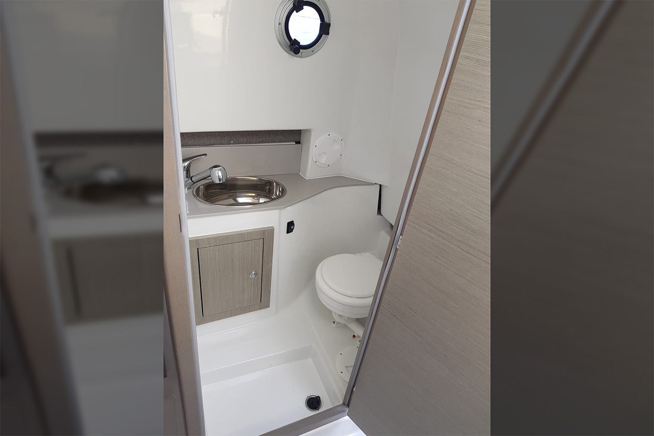 Unutarnji pogled na modernu i kompaktnu kupaonicu s umivaonikom, WC-om i tušem, tipičnu za luksuzni gumenjak