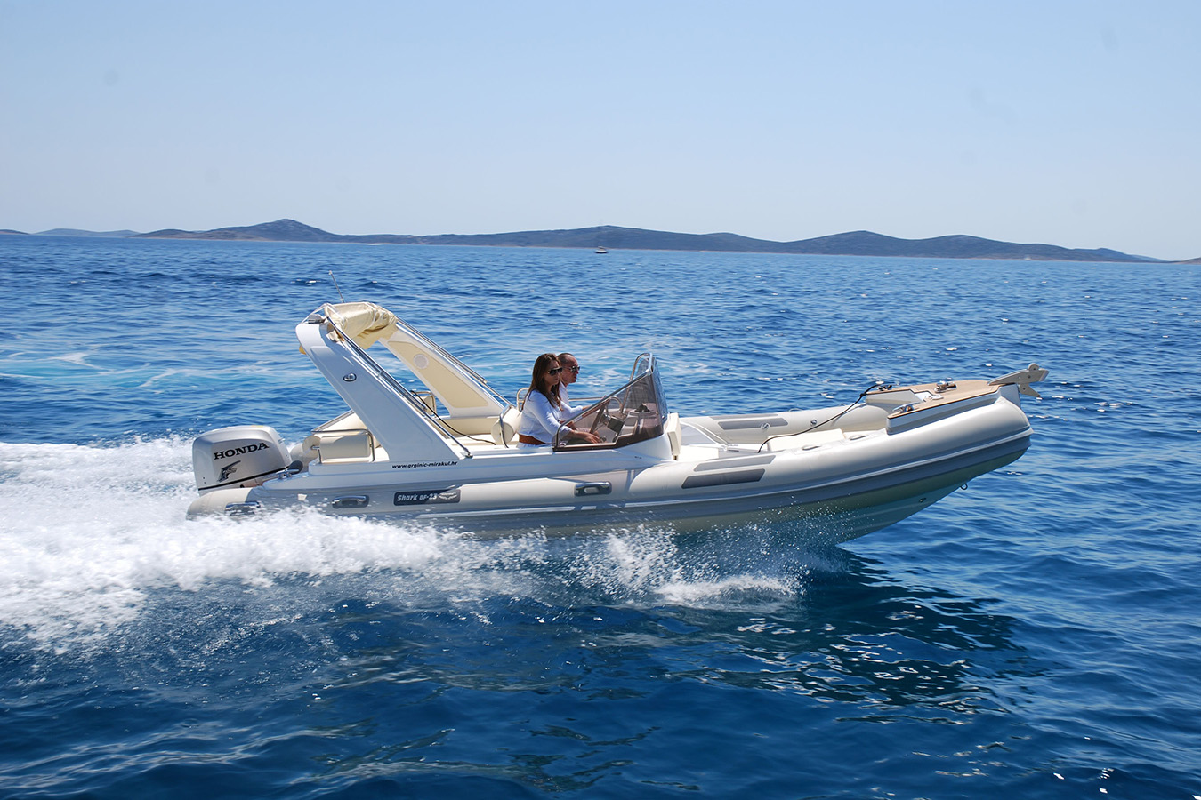 elegantan Shark RIB u vožnji s parom na skiperskim sjedalima, svijetli tubusi, Honda izvanbrodski motor i kristalno plavo more; dinamično luksuzna plovila za dnevne izlete
