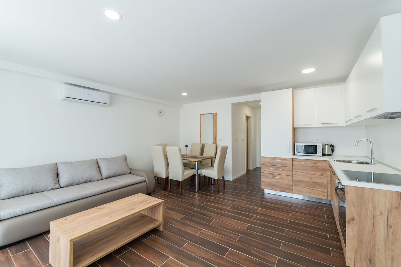 Svijetli, otvoreni interijer apartmana s udobnom sivom sofom, modernim drvenim stolićem za kavu, blagovaonicom sa stolom i šest stolica te potpuno opremljenom kuhinjom, što predstavlja izvrsne apartmane za odmor Vir