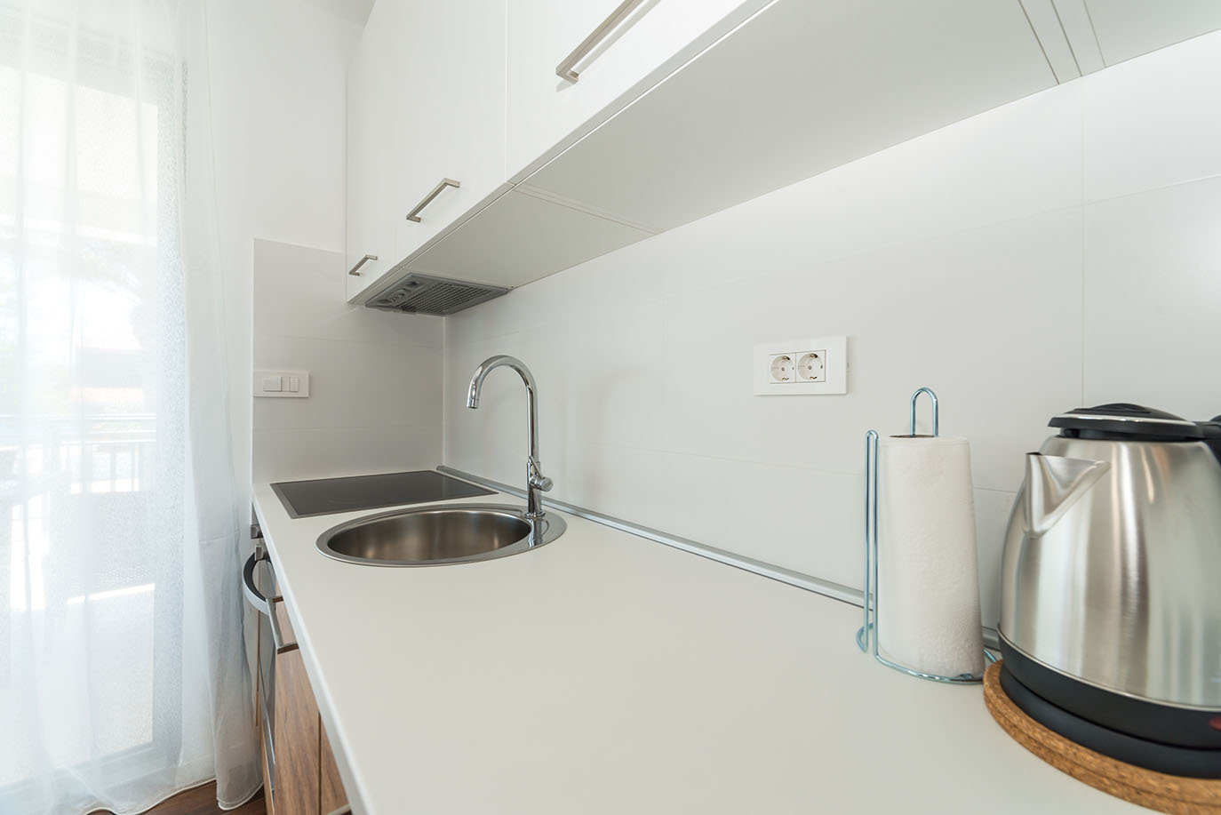 Moderna i svijetla kuhinja apartmana na Viru, s inox sudoperom, električnom pločom za kuhanje, bijelim gornjim ormarićima i kuhalom za vodu