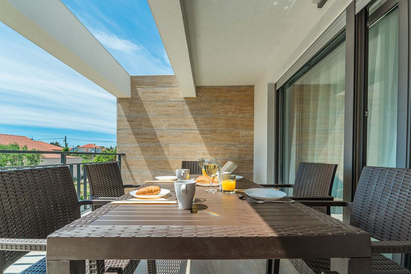 Svijetli, sunčani balkon s doručkom na stolu, uključujući kroasane i pića, idealno vanjsko okruženje za posjetitelje koji uživaju u apartmanima Vir