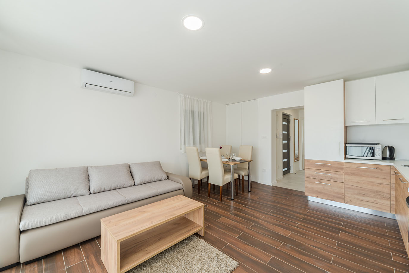 Svijetli i moderni otvoreni prostor s dnevnim boravkom, blagovaonicom i kuhinjom, karakterističan za apartmani Vir, opremljen udobnom sofom, drvenim stolićem, blagovaonskim setom i dobro opremljenom kuhinjom