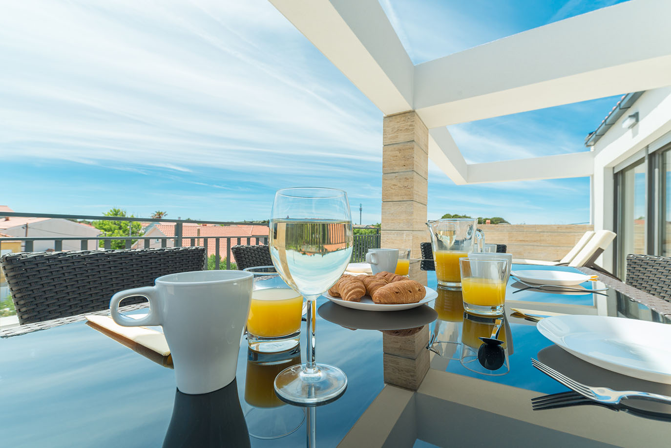 Bogat doručak s kroasanima, sokom od naranče i kavom poslužen na sunčanom balkonu s prekrasnim pogledom, kakav se nudi u apartmanima Vir