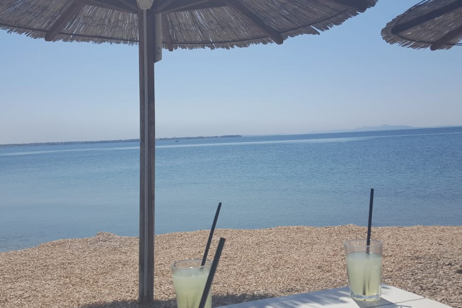 View from under a parasol toward the calm sea with two lemonades on the table on Vir Island