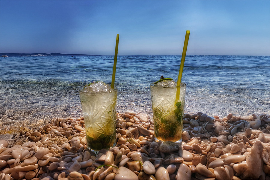 Two cocktails on pebbles right by the crystal-clear sea on Vir Island